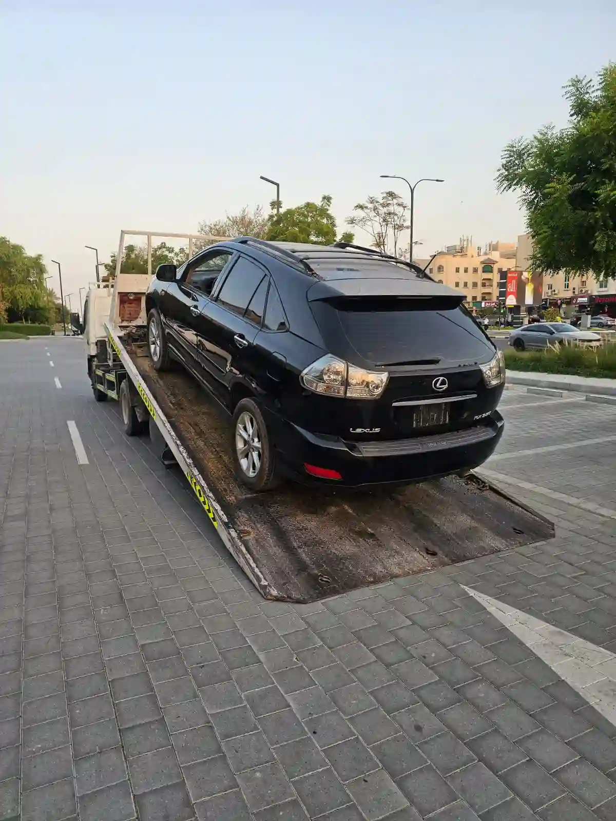 Black Lexus RX 350 loaded onto a flatbed recovery truck for towing and salvage