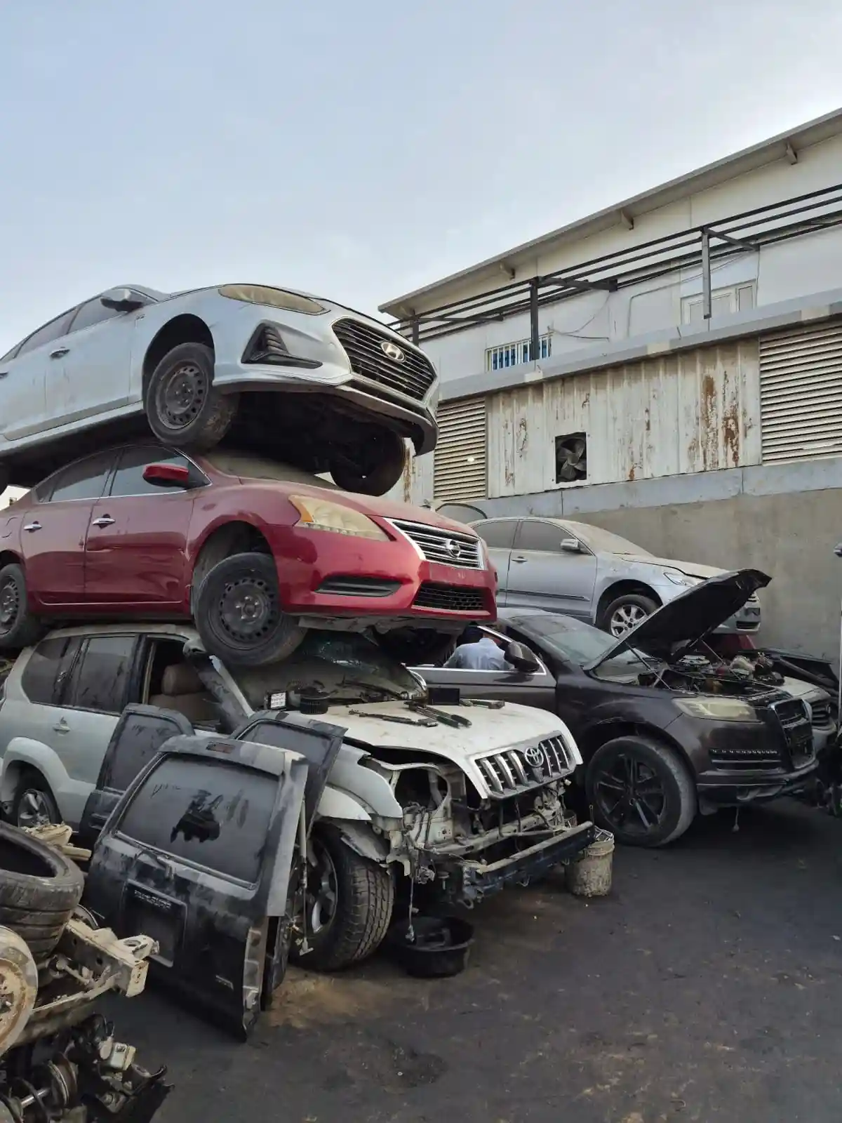 Damaged scrap vehicles stacked vertically in an auto salvage yard